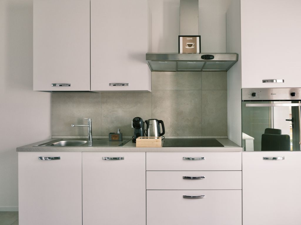 Cucina moderna con lavello, piano cottura, forno e cappa in acciaio inox.