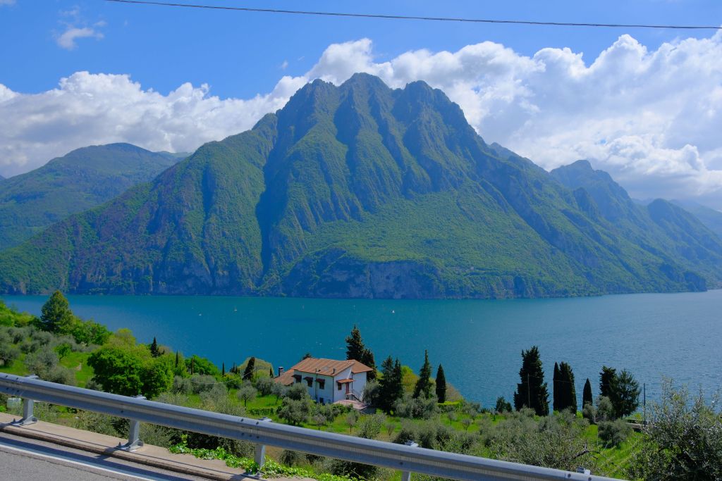Vista panoramica su lago e montagna verde con cielo azzurro e nuvole bianche