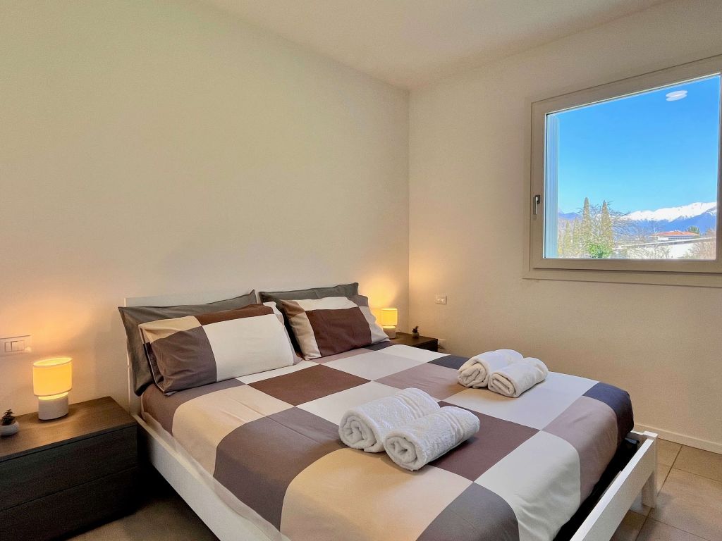 Camera da Bett con Bett matrimoniale, cuscini a quadri e finestra con vista montagna.