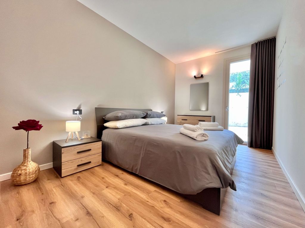 Camera da letto con letto matrimoniale, comodini, lampada e porta finestra con tenda scura