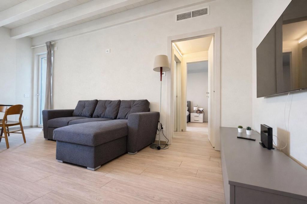 Soggiorno moderno con divano grigio, lampada da terra e TV a schermo piatto