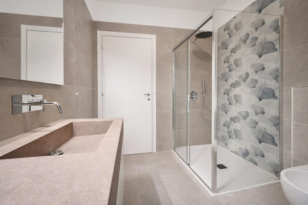 Bagno moderno con lavabo integrato in pietra e doccia con parete decorata