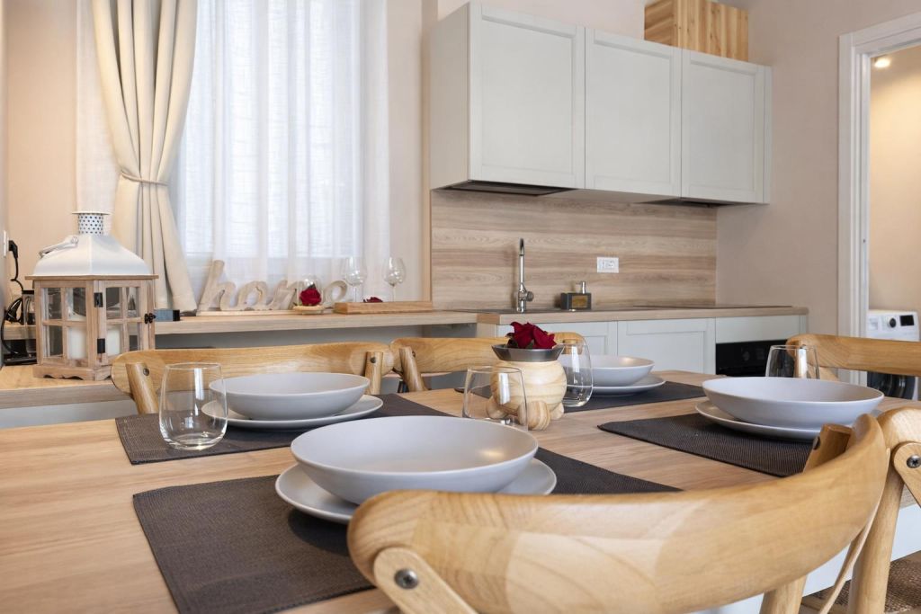 Cucina moderna con tavolo in legno apparecchiato e mobili bianchi
