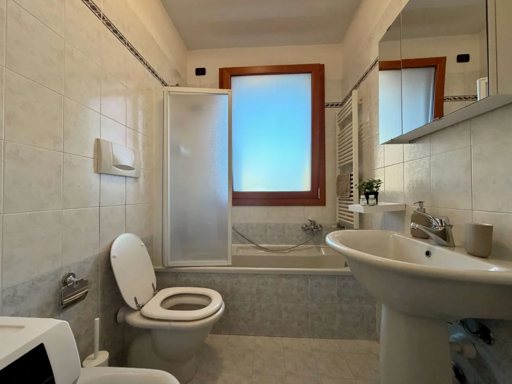 Bagno con vasca, doccia, lavabo, wc e finestra con vetro satinato
