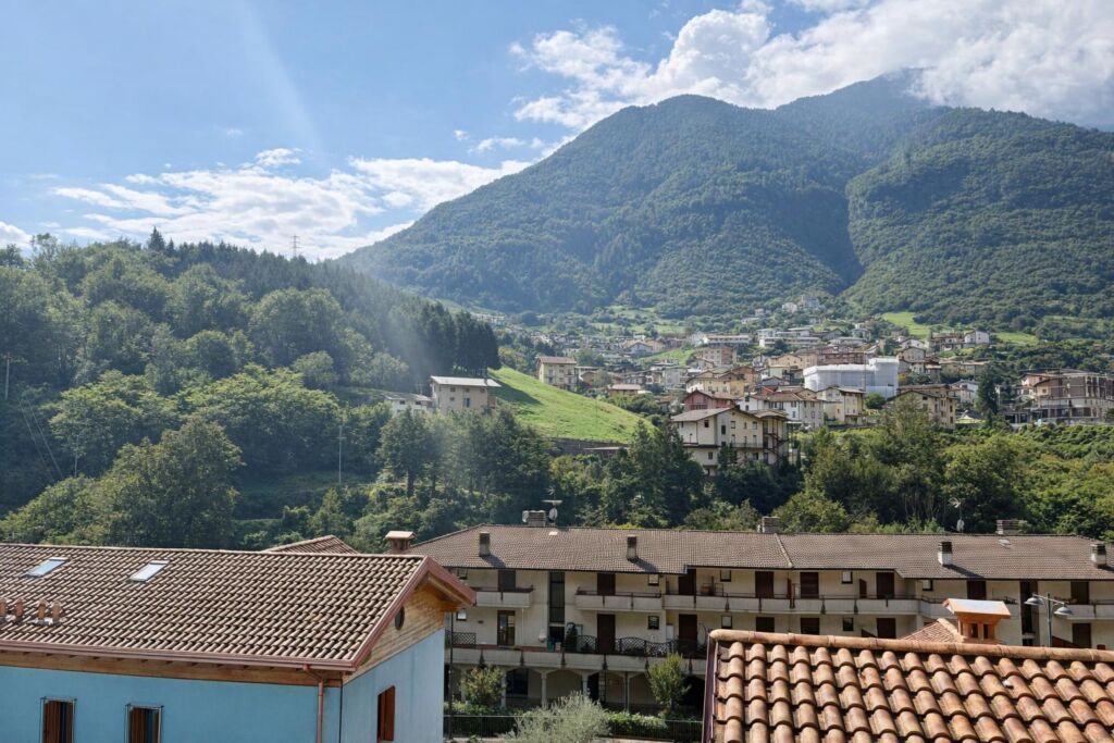 Vista panoramica su case e montagne verdi con cielo parzialmente nuvoloso